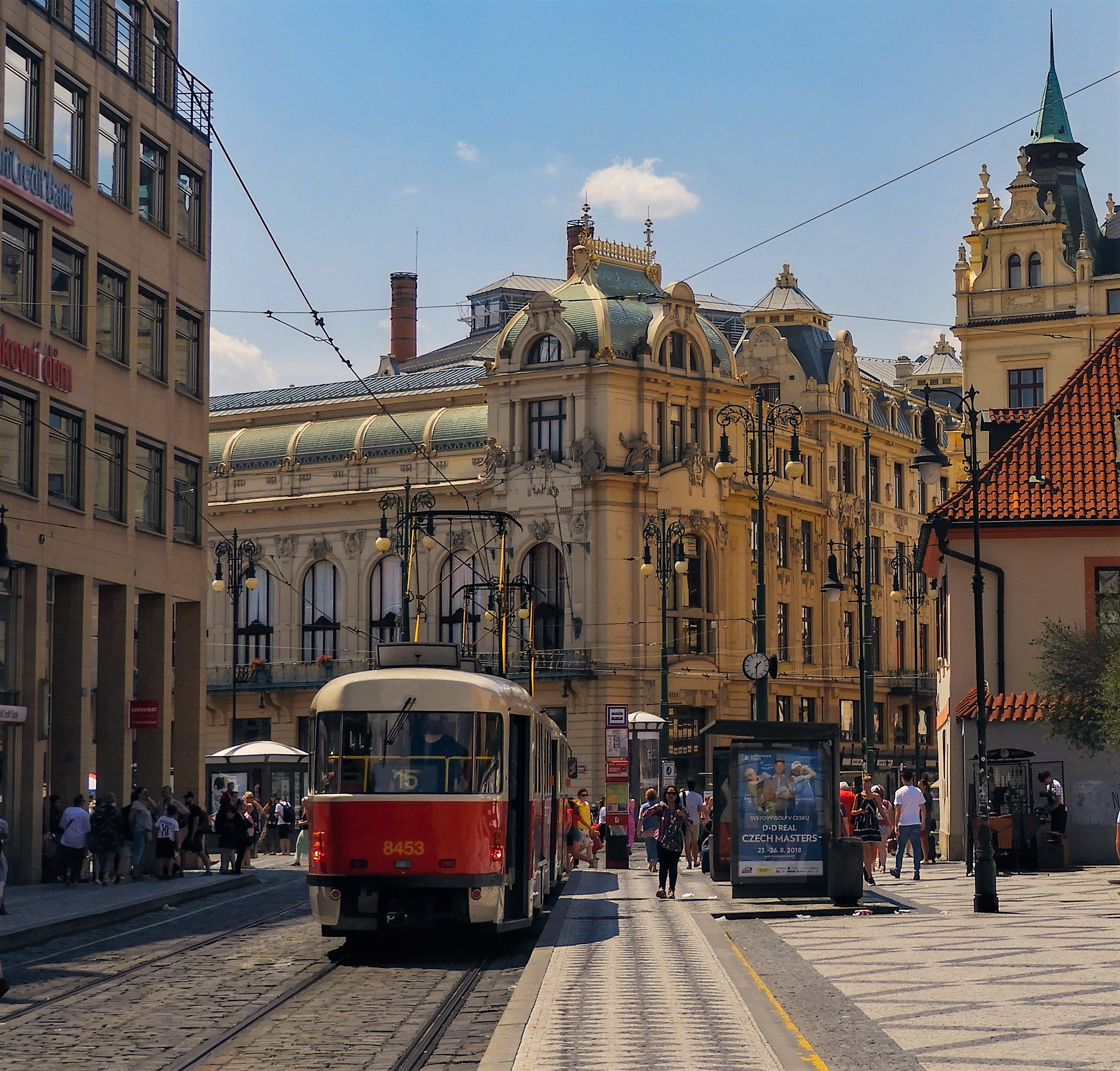 Pohled k nedaleké tramvajové zastávce do ulice Na Poříčí ve směru Bílá labuť nebo Masarykovo nádraží. Také v tomto směru je ostrůvek sice součástí chodníku, ale je vyvýšen na asi dvou schůdcích. Je zde i přistřešek a poměrně málo místa. Na vymezenou tramvajovou zastávku se dostanete bez přecházení ulice. I v protisměru zastavují tramvaje přímo u nástupiště tramvaje. Nemusí se přecházet ulice.